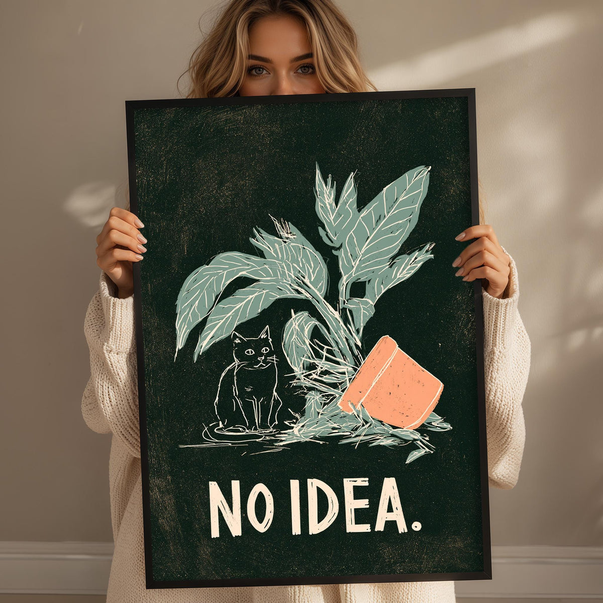 A woman is holding up a framed poster with a black background and a green plant illustration. The poster has the text "NO IDEA." written on it.