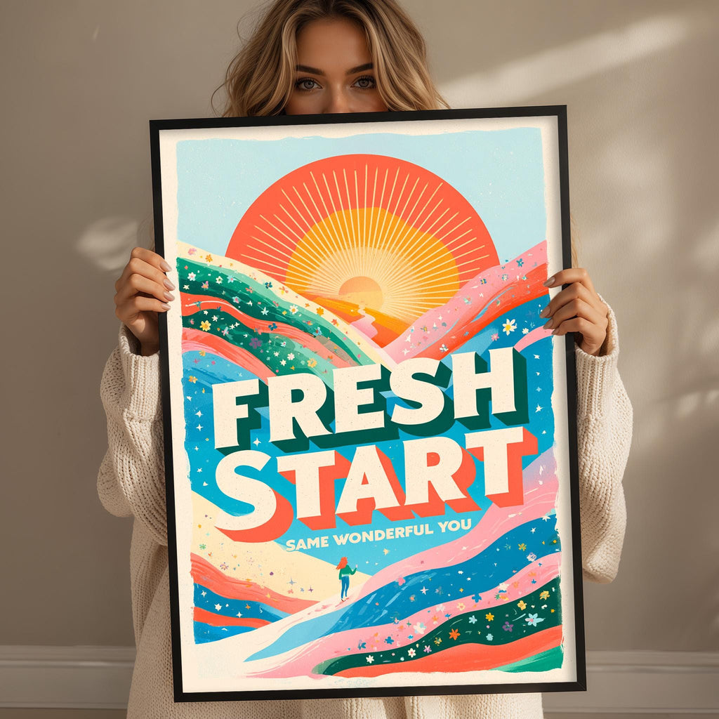 A woman holding a framed poster with a colorful, abstract design featuring a sun and mountains.