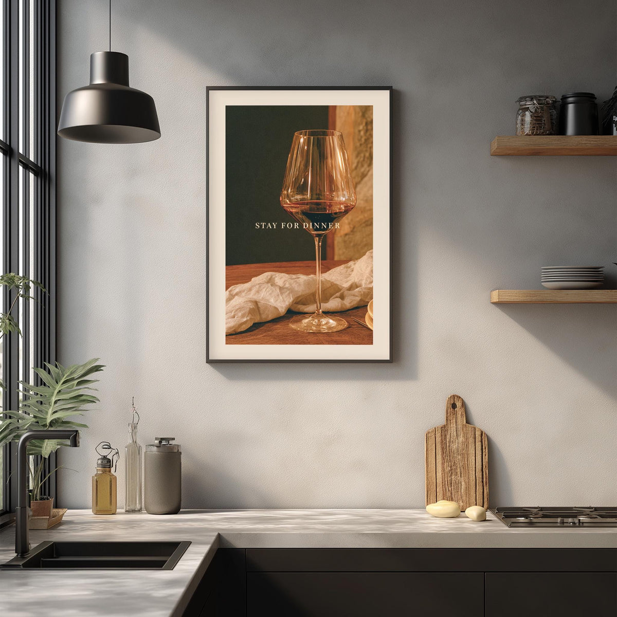 a framed picture of a wine glass on a kitchen counter, with the text "STAY FOR DINNER" displayed on the glass.
