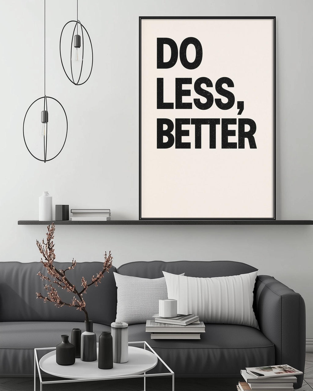 a modern living room with a gray sofa, a coffee table, and a large framed poster with the text "DO LESS, BETTER" displayed on the wall above the sofa.