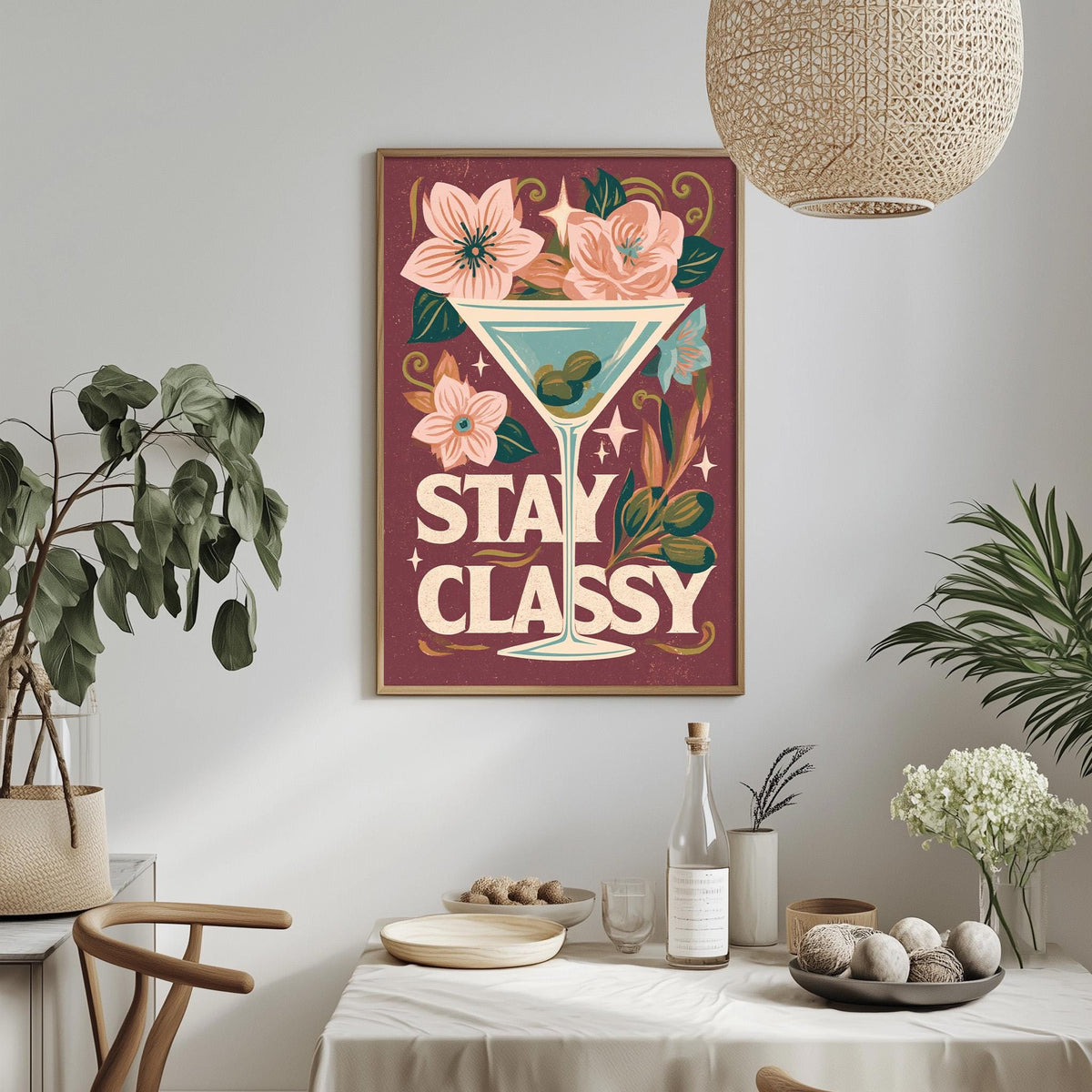 a framed poster with a cocktail glass and flowers, hanging on a wall above a dining table with various decorative items and plants.