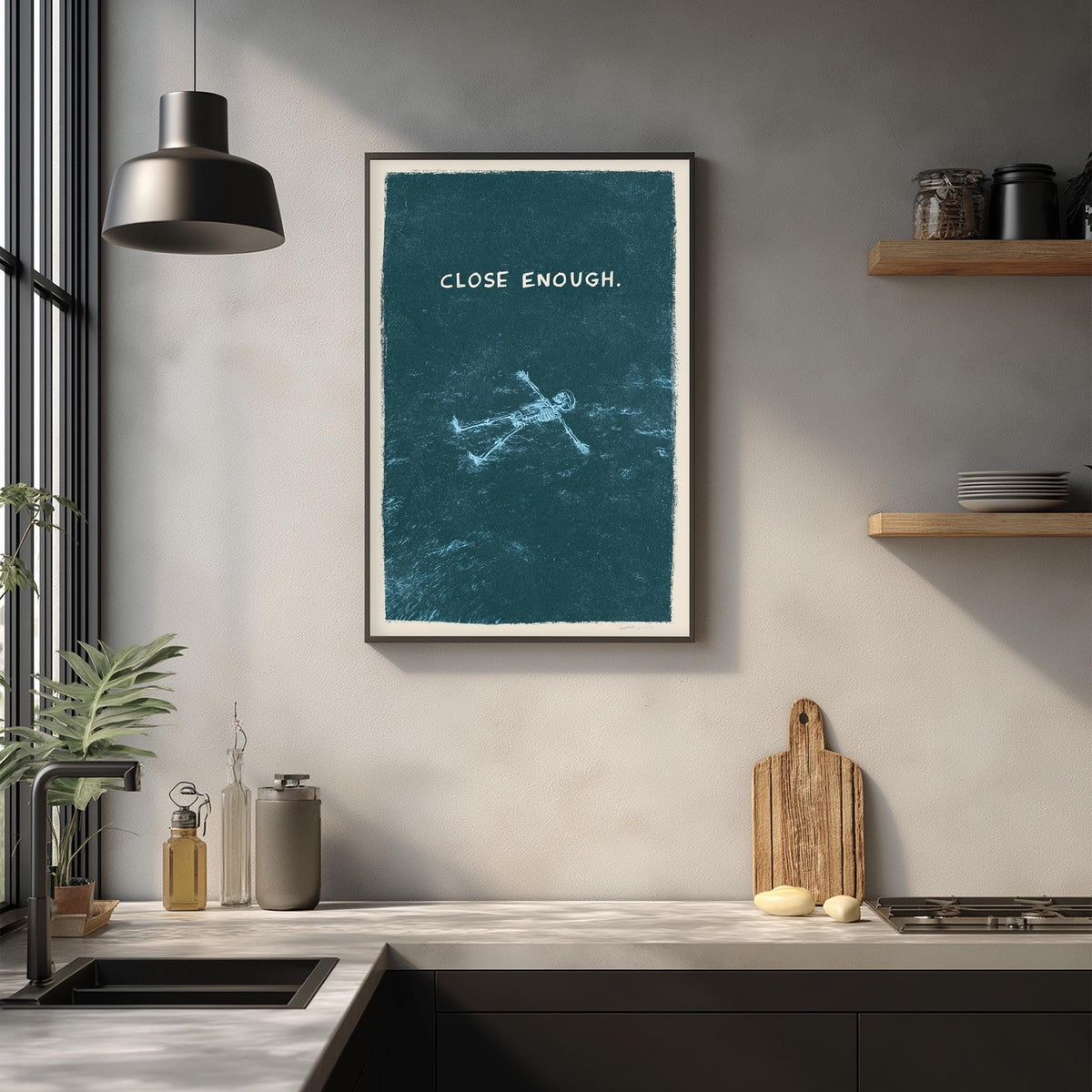a kitchen counter with a framed poster of a person floating in water, a wooden cutting board, and various kitchen items such as a bottle, a vase, and a bowl.