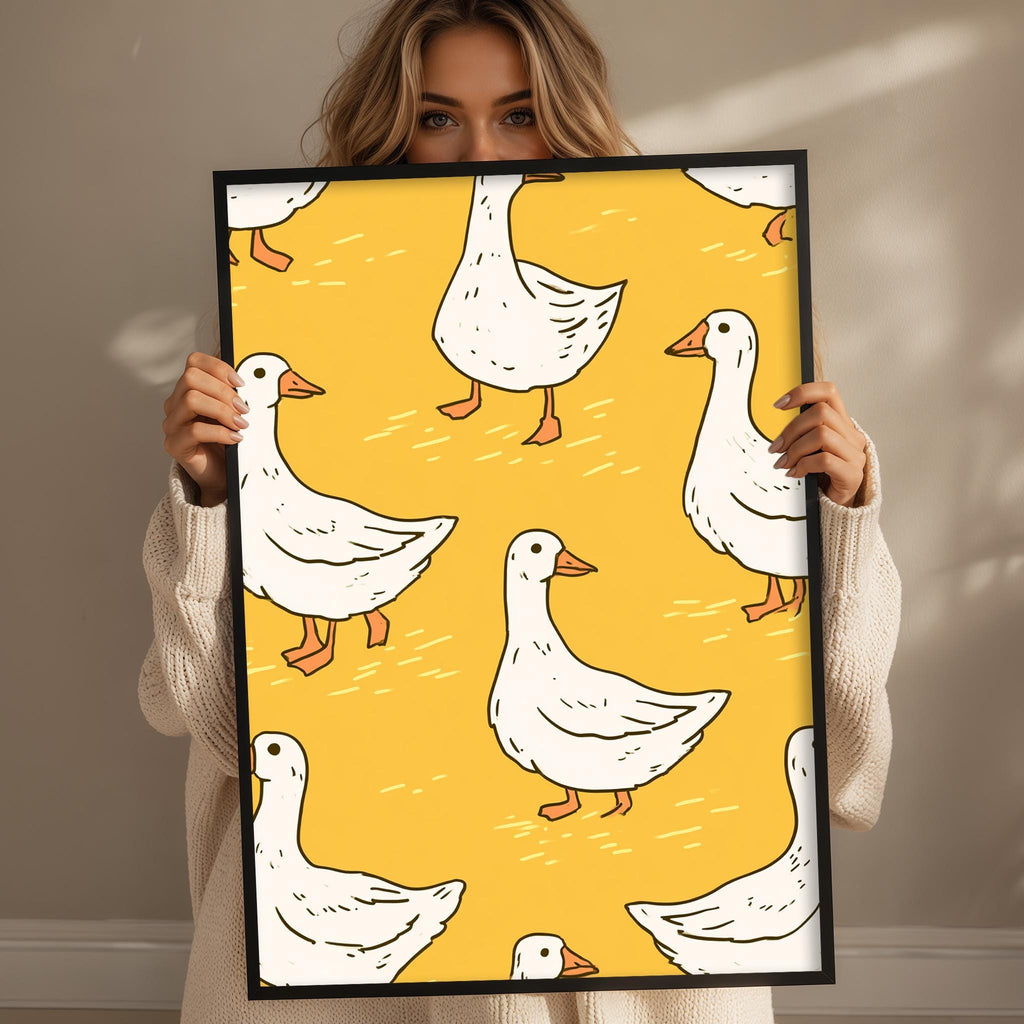 A woman is holding up a framed print with a repeating pattern of white ducks on a yellow background.