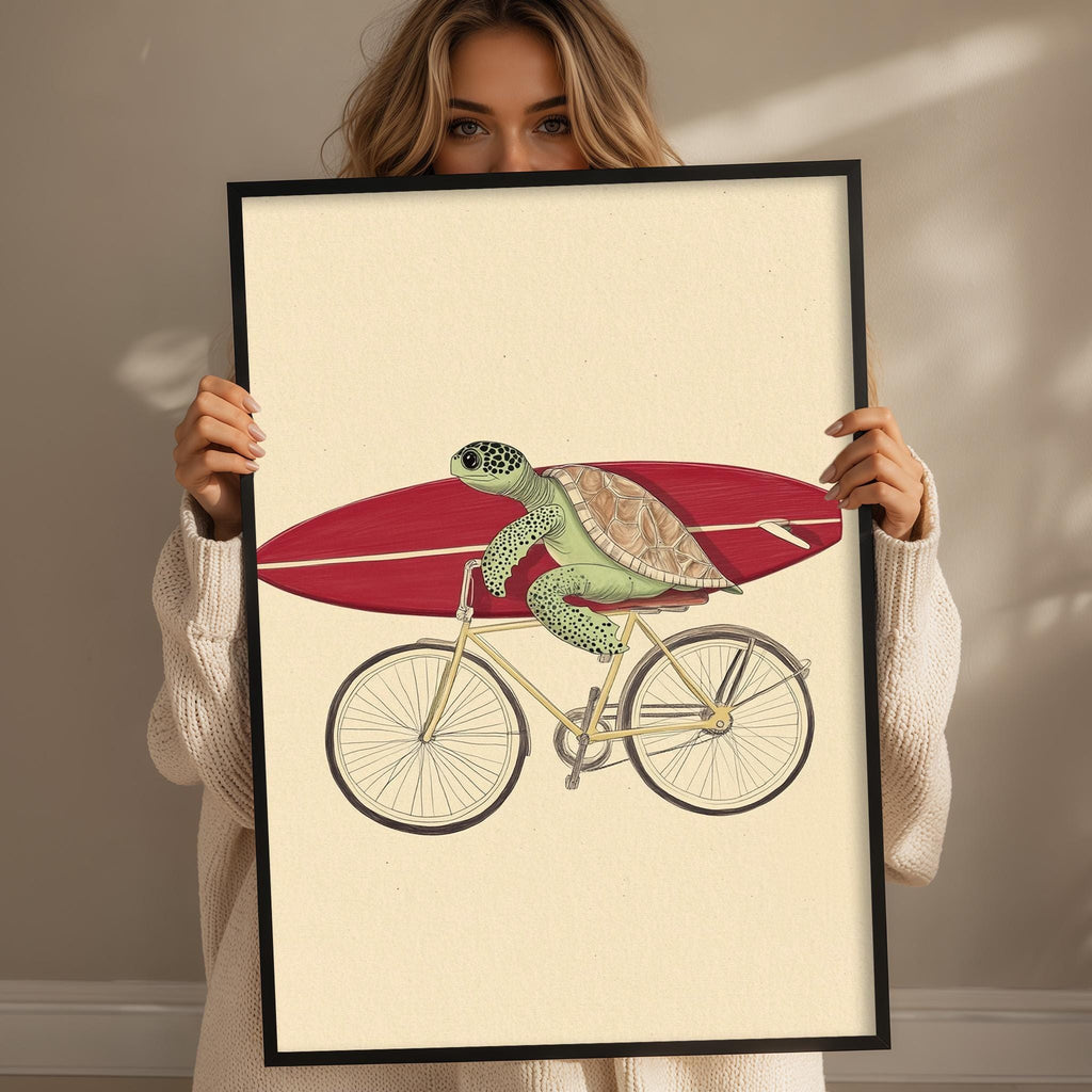 A woman is holding a framed print that depicts a turtle riding a bicycle.