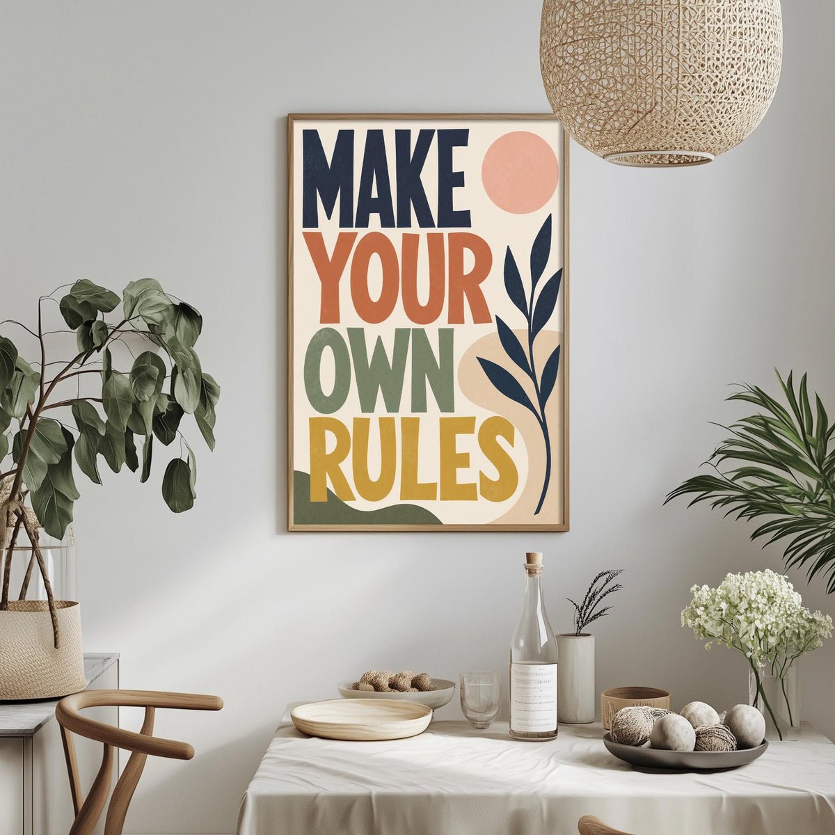 a framed poster with the text "MAKE YOUR OWN RULES" hanging on a wall above a dining table with various decorative items and plants.
