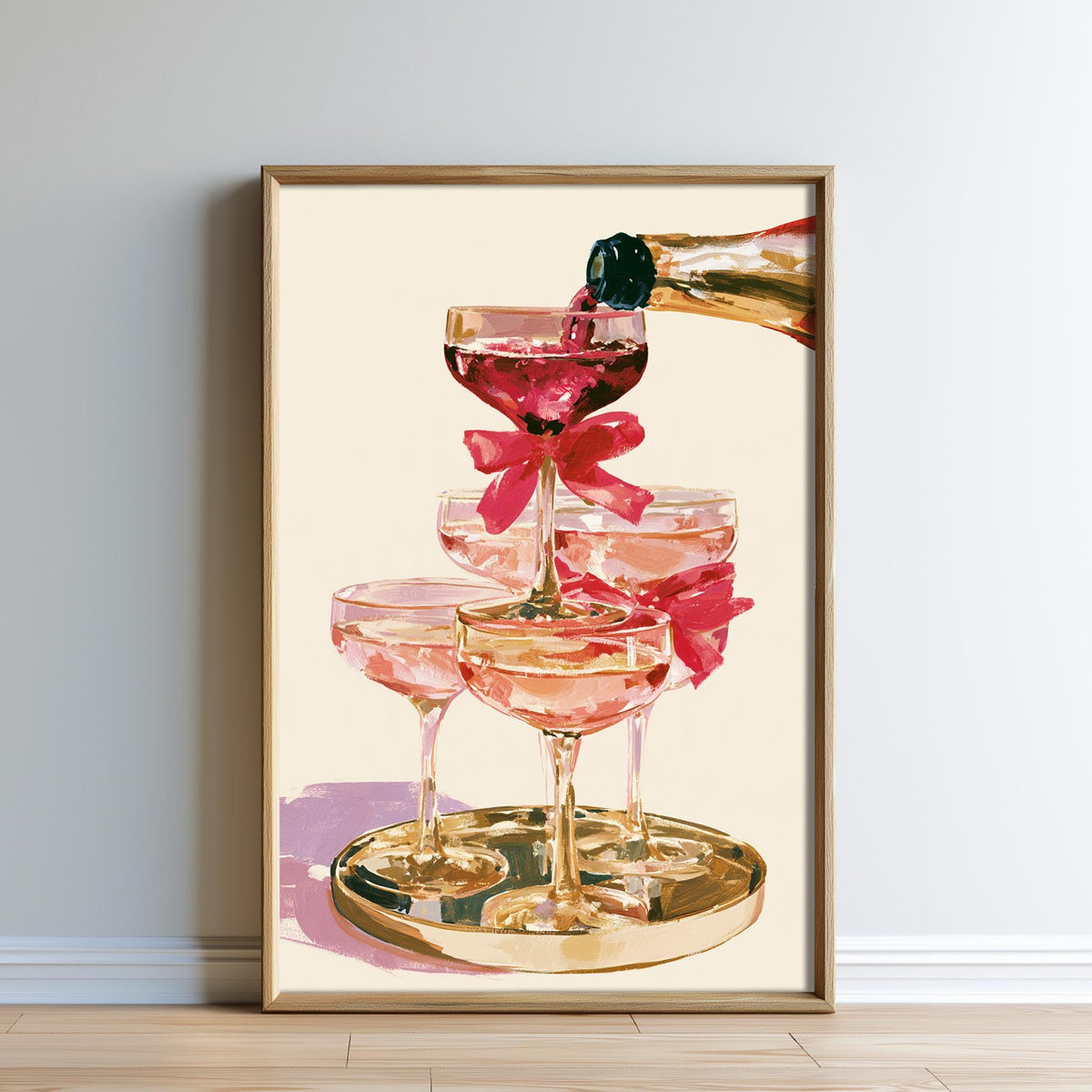 A framed painting depicting a champagne bottle being poured into a stack of champagne glasses, with pink ribbons on the glasses.