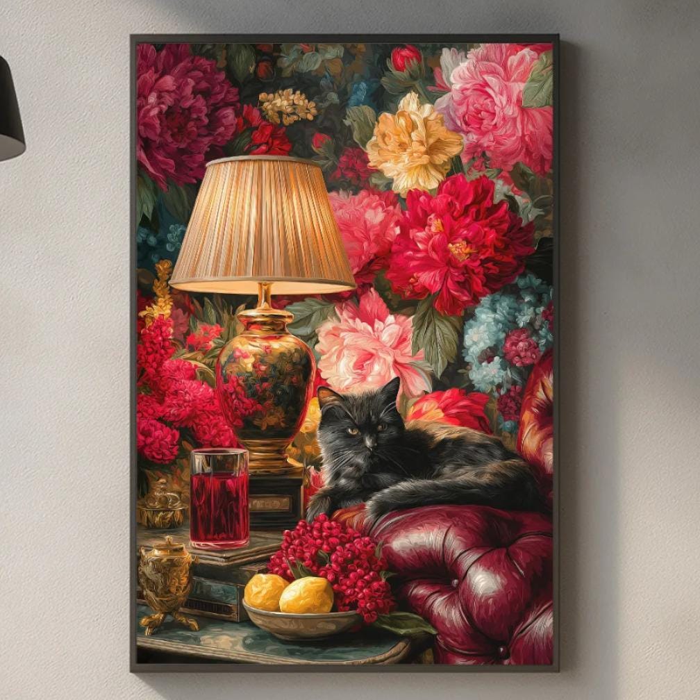 a kitchen scene with a framed painting of a cat resting on a table surrounded by a variety of colorful flowers, including red, pink, and yellow blooms. The painting is hanging on a wall above a kitchen counter with various kitchen items such as a lamp, a bowl, and a cutting board.