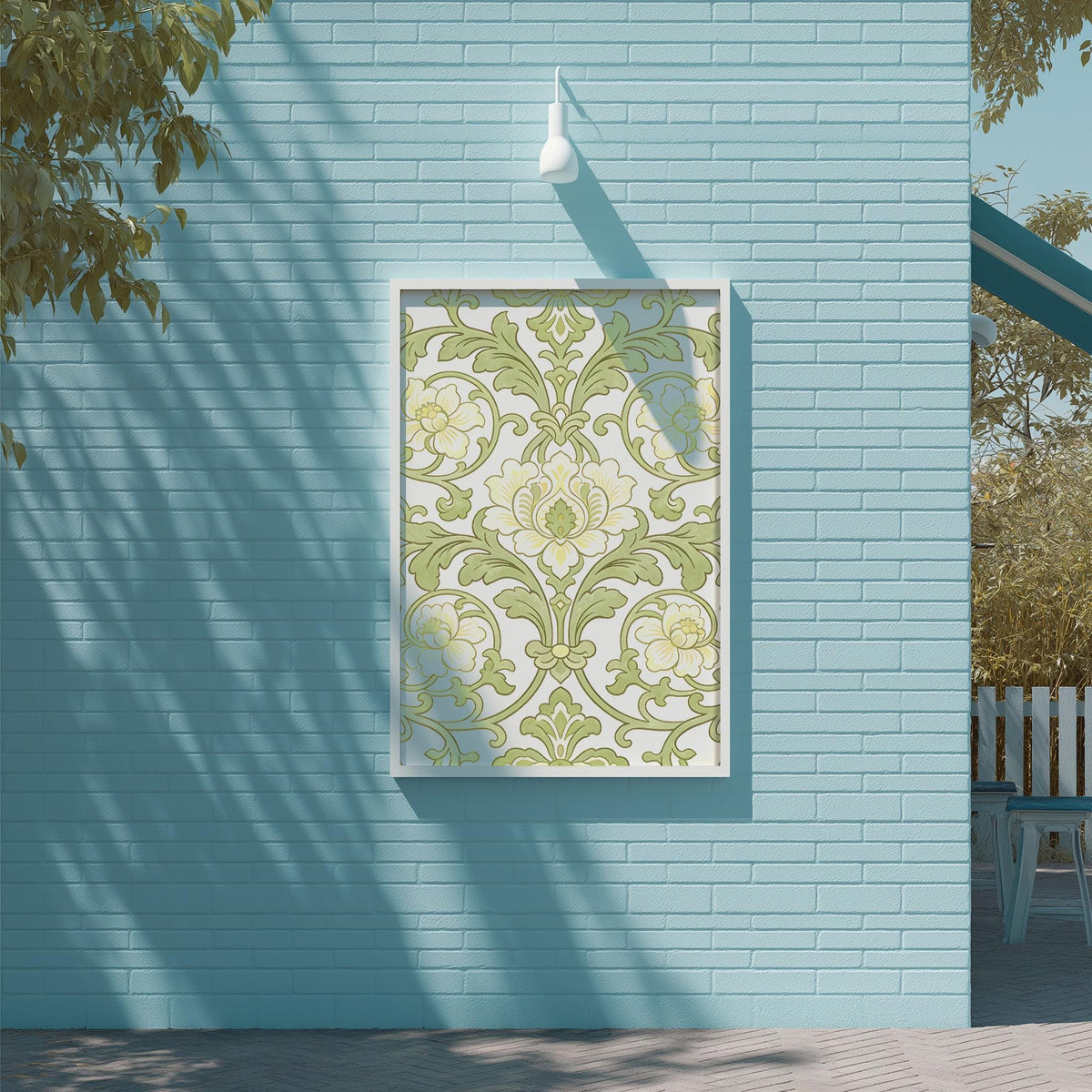 a blue brick wall with a framed picture hanging on it. The picture has a floral pattern in shades of green and white. The wall is situated next to a wooden deck and a tree, creating a serene outdoor setting.