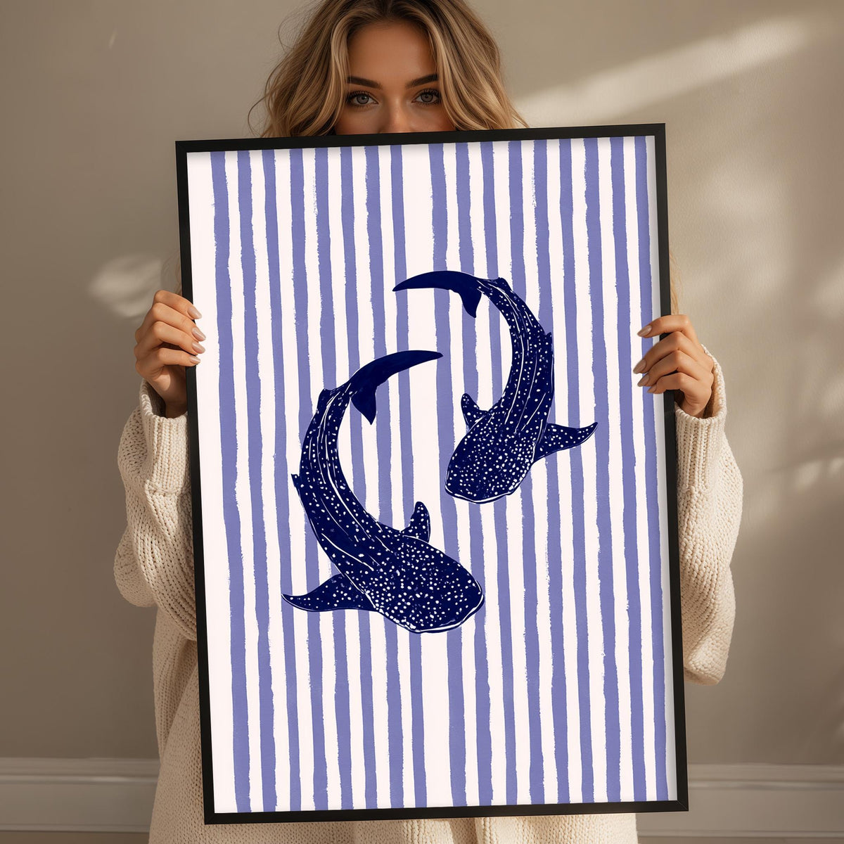 A woman is holding up a framed print with a blue and white striped pattern.