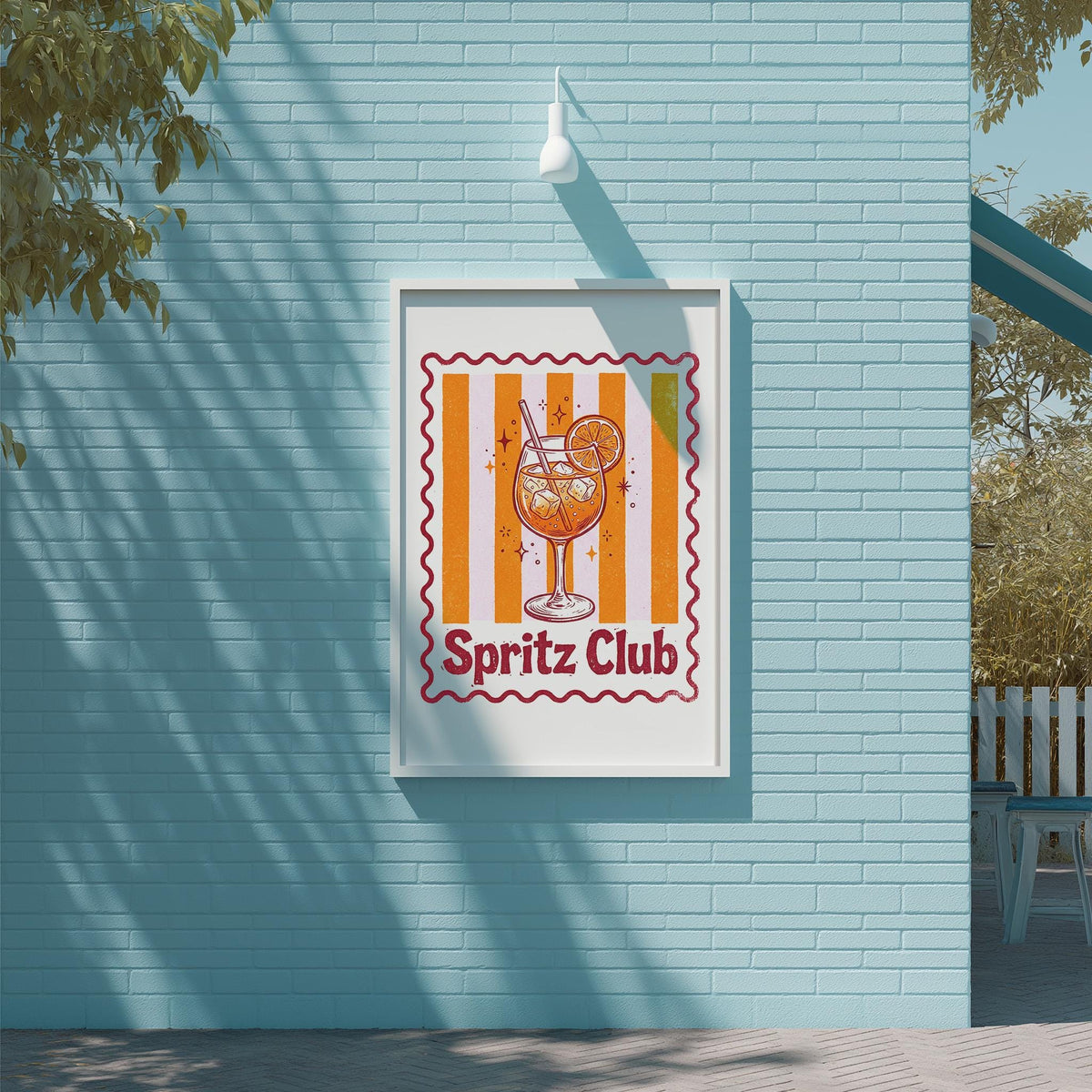 A framed poster of a glass of orange juice with a red and white striped border, hanging on a blue wall.
