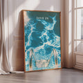 a framed poster with a blue and white ocean scene, featuring a pair of diving fins and the text "DIVE IN".