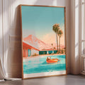 A framed painting depicting a person relaxing on a float in a pool, with palm trees and mountains in the background.