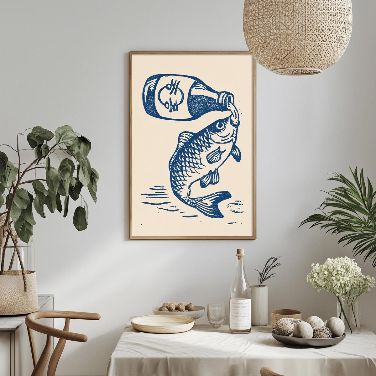 a framed illustration of a fish with a bottle of beer above it, hanging on a wall above a dining table with various items on it.