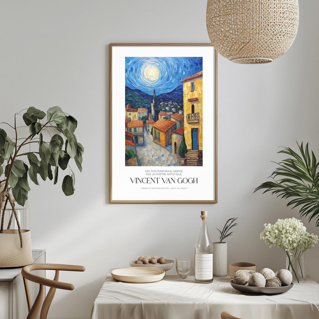 a framed painting of a colorful village scene hanging on a wall, with a dining table and chairs in the foreground.
