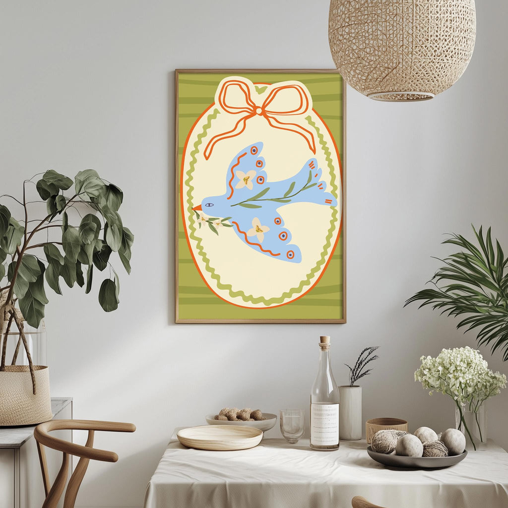 a dining table with a white tablecloth, a bowl of fruit, a bottle, and a vase with flowers. Above the table, there is a framed picture of a bird with a bow around its neck.