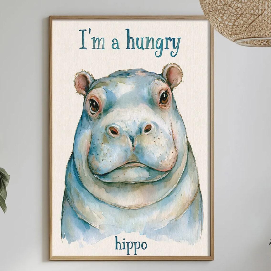a framed poster of a hippopotamus with the text "I'm a hungry hippo" on it, hanging on a wall above a dining table with various items on it.