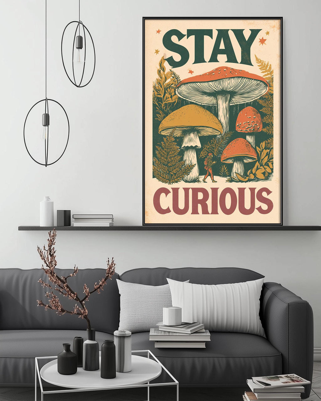 a framed poster with the text "STAY CURIOUS" displayed on a wall above a gray couch with a coffee table in front of it.