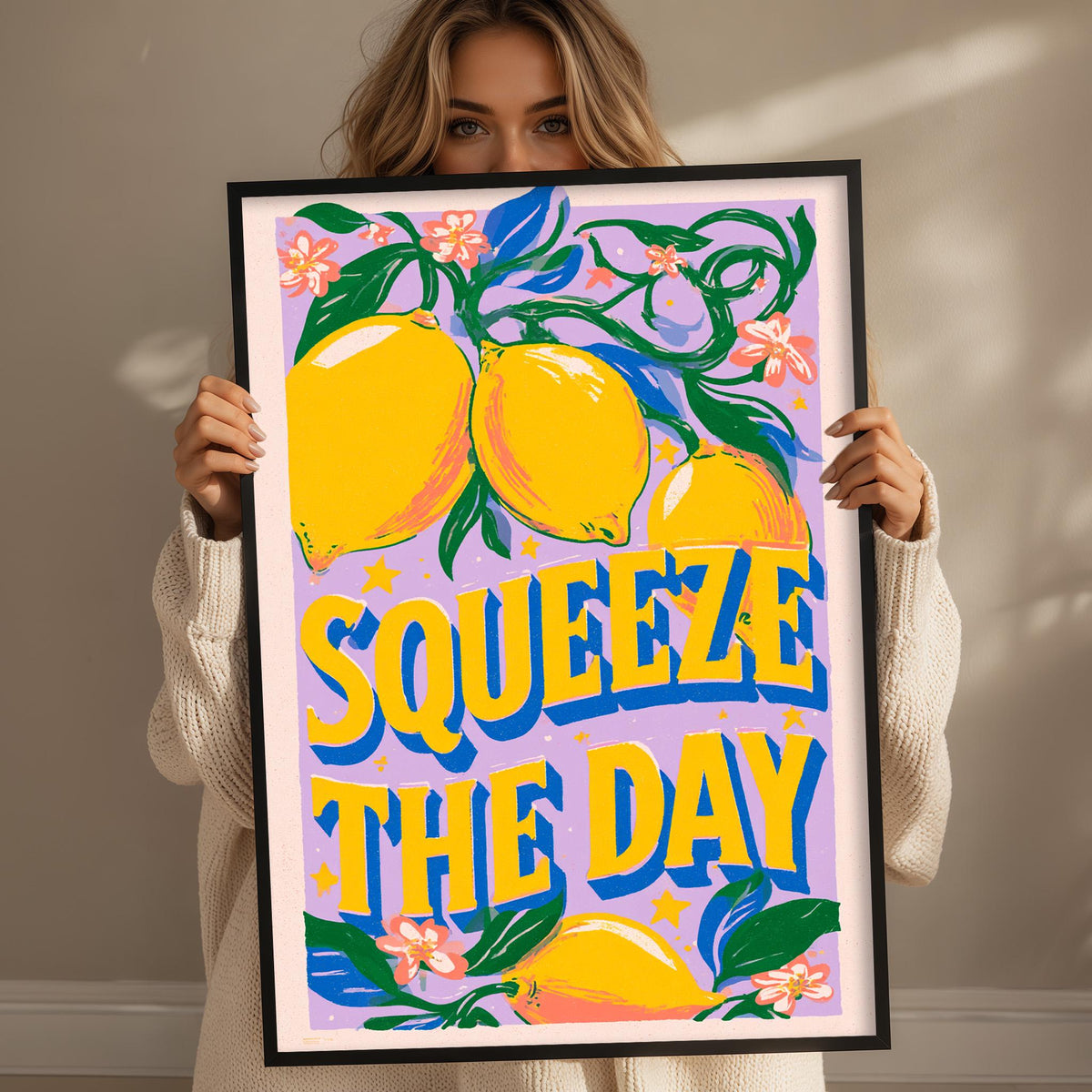 A woman holding a framed poster with a vibrant design featuring lemons and flowers.