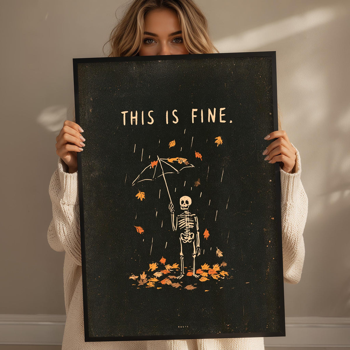 A woman holding a framed poster with a skeleton standing in the rain, surrounded by fallen leaves.