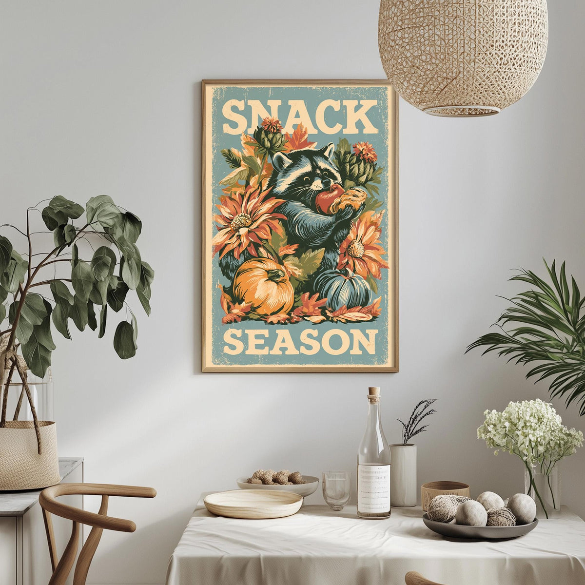 a framed poster with a raccoon and flowers, hanging on a wall above a dining table with various items on it.