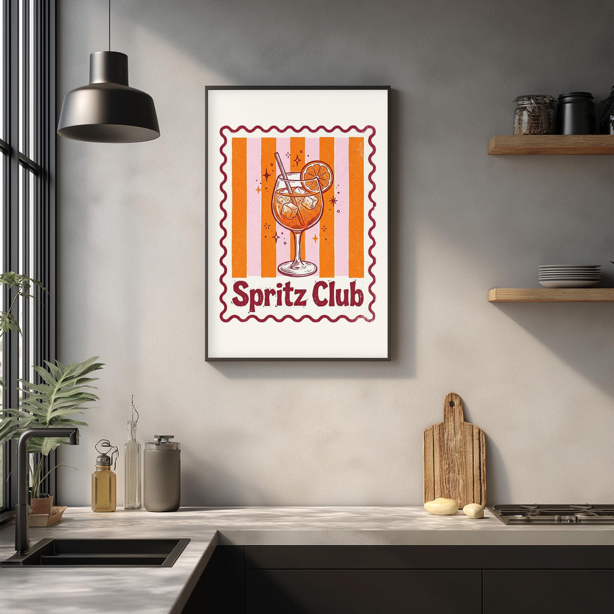 a framed poster of a glass of orange drink with a striped pattern, hanging on a wall above a kitchen counter with various kitchen items and a potted plant.