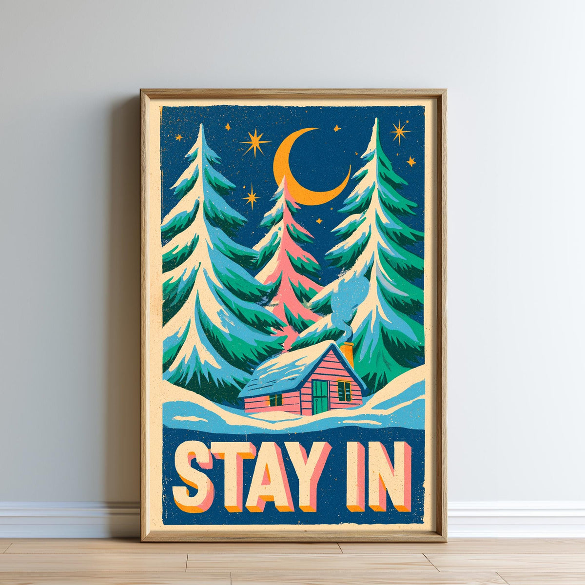 A framed poster with a winter scene depicting a cabin surrounded by pine trees and a crescent moon in the night sky.