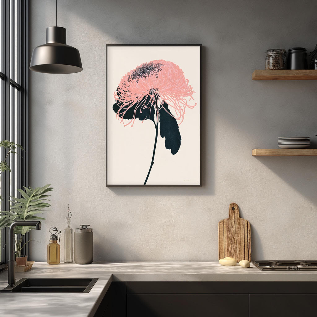 a kitchen counter with a framed artwork of a pink flower hanging above it. The counter also has various kitchen items such as a cutting board, a bottle, and a bowl.