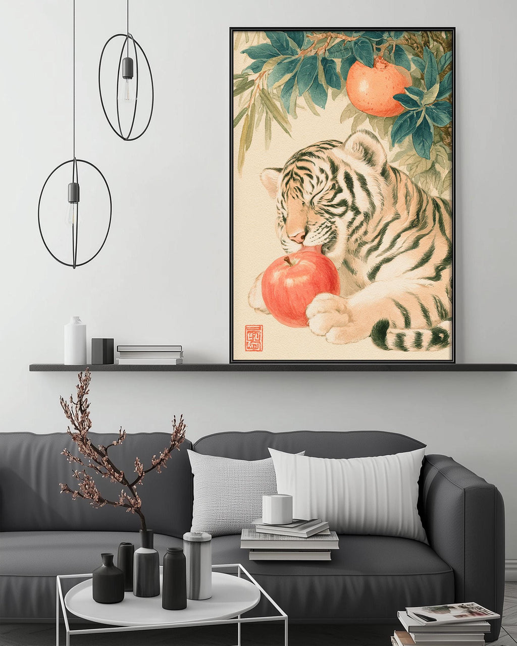 a tiger sitting on a branch and eating an orange, with a framed painting of a tiger and an orange hanging on the wall above a gray couch.