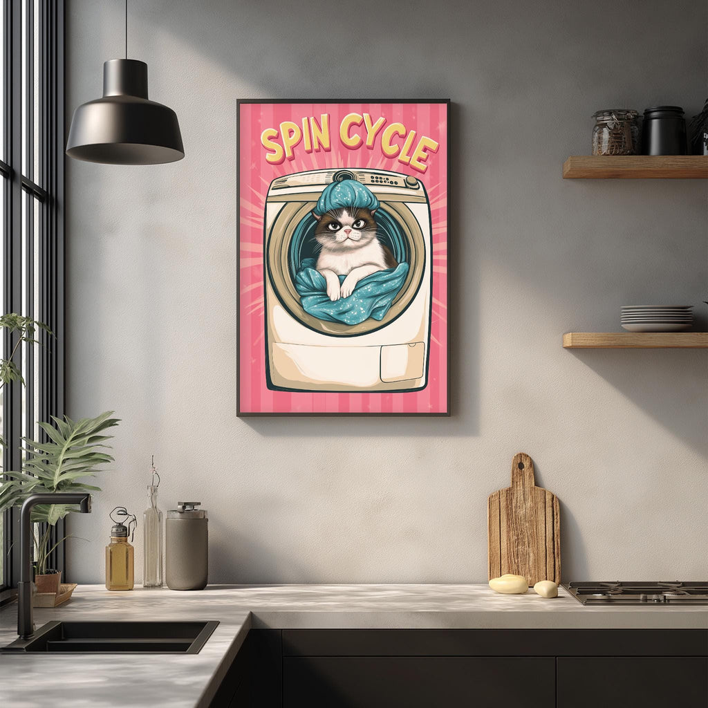 a kitchen counter with various items, including a framed poster of a cat inside a washing machine, a wooden cutting board, and a potted plant.