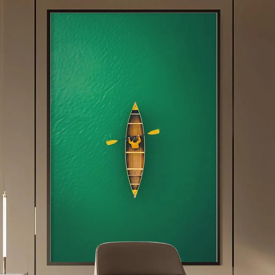 a modern office space with a large green wall art piece featuring a boat on the water. The office has a wooden desk, a comfortable-looking chair, and a bookshelf filled with books. The overall design and decor create a calm and professional atmosphere.