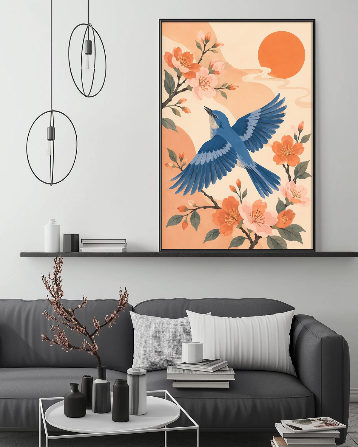 a large framed artwork depicting a blue bird in flight above a floral scene, with orange and pink flowers and a sun in the background. The artwork is displayed on a wall above a gray couch, which has a coffee table and decorative items on it.