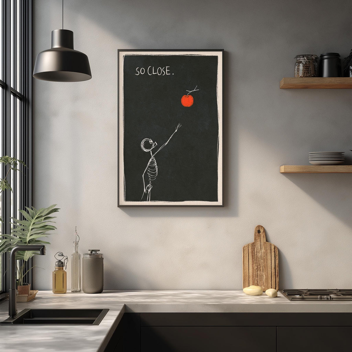 a kitchen counter with various kitchen items, such as a cutting board, a bottle, and a bowl. Above the counter, there is a framed drawing of a skeleton reaching for an orange, accompanied by the text "So Close."