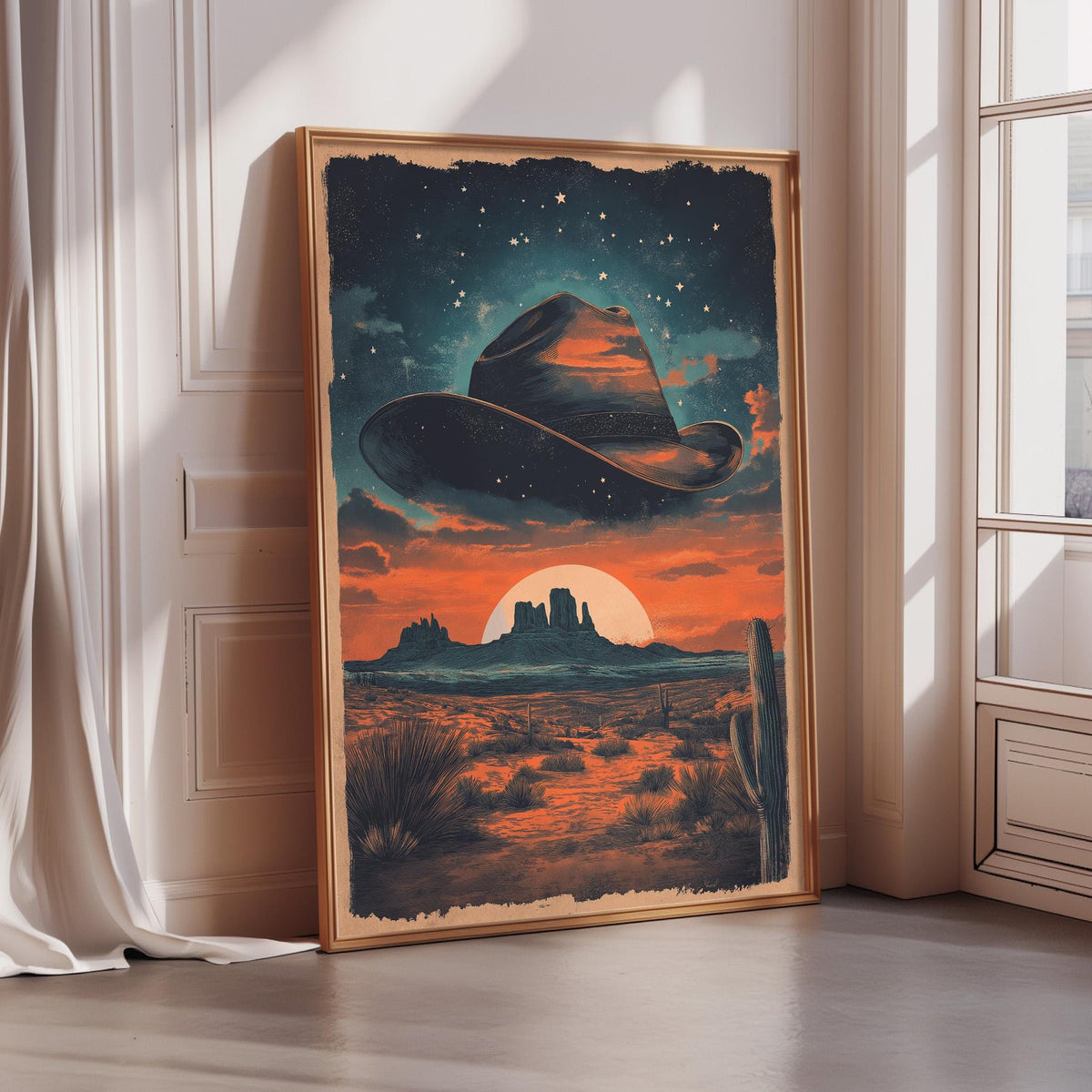 a framed painting depicting a desert landscape with a cowboy hat in the sky, a cactus, and a sunset.