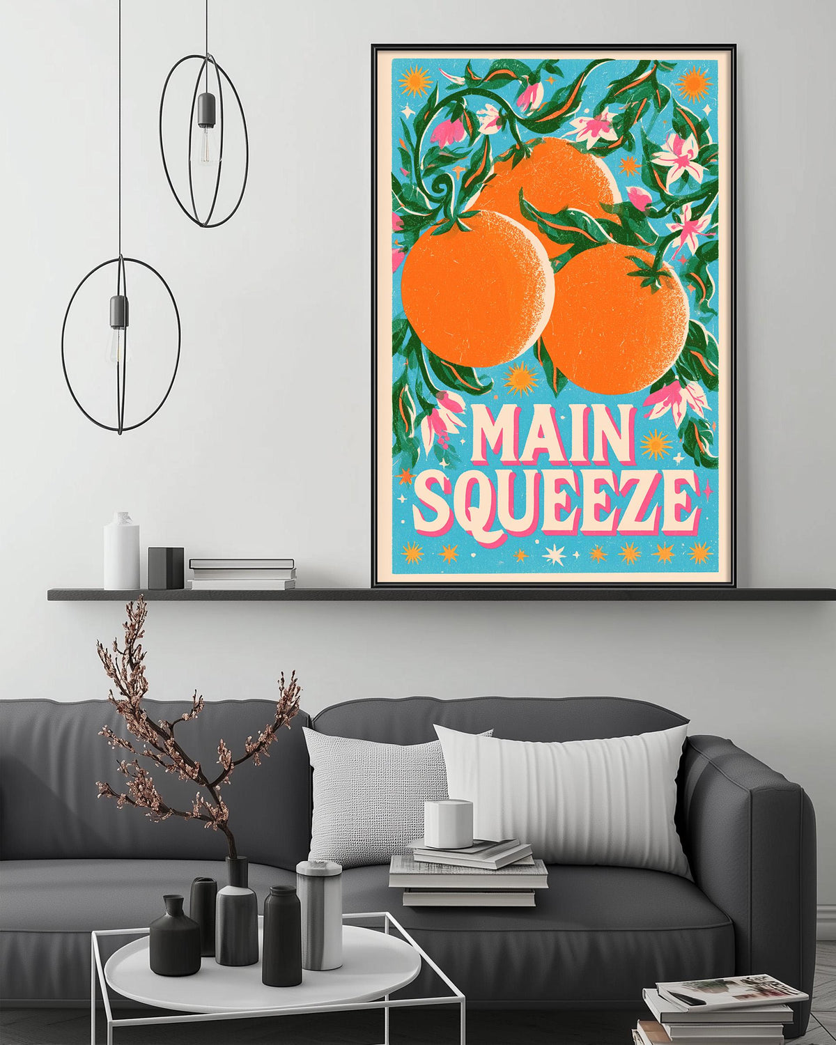a large framed poster of oranges hanging on a wall above a gray couch in a living room setting.