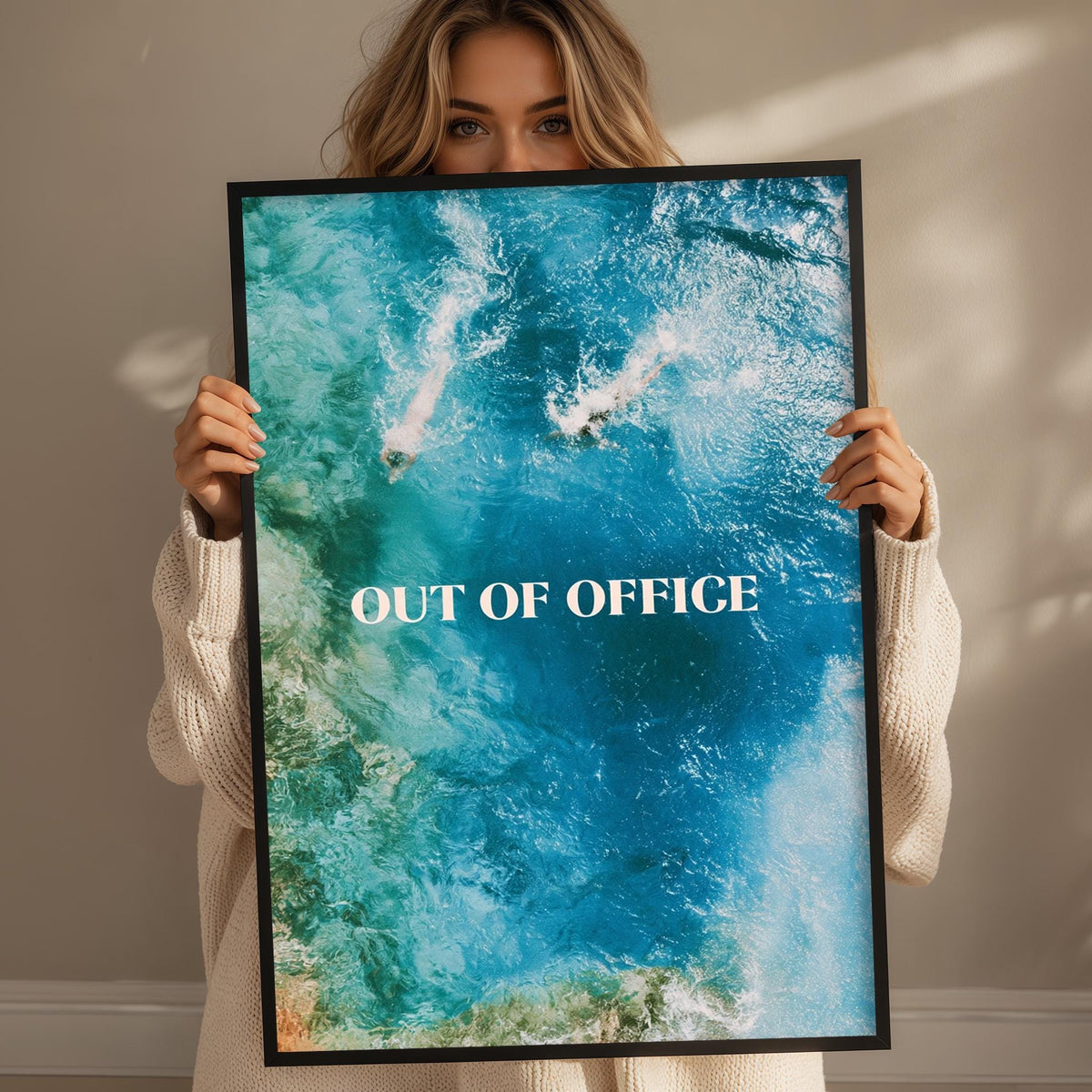 A woman holding a framed poster with the text "OUT OF OFFICE" on it.