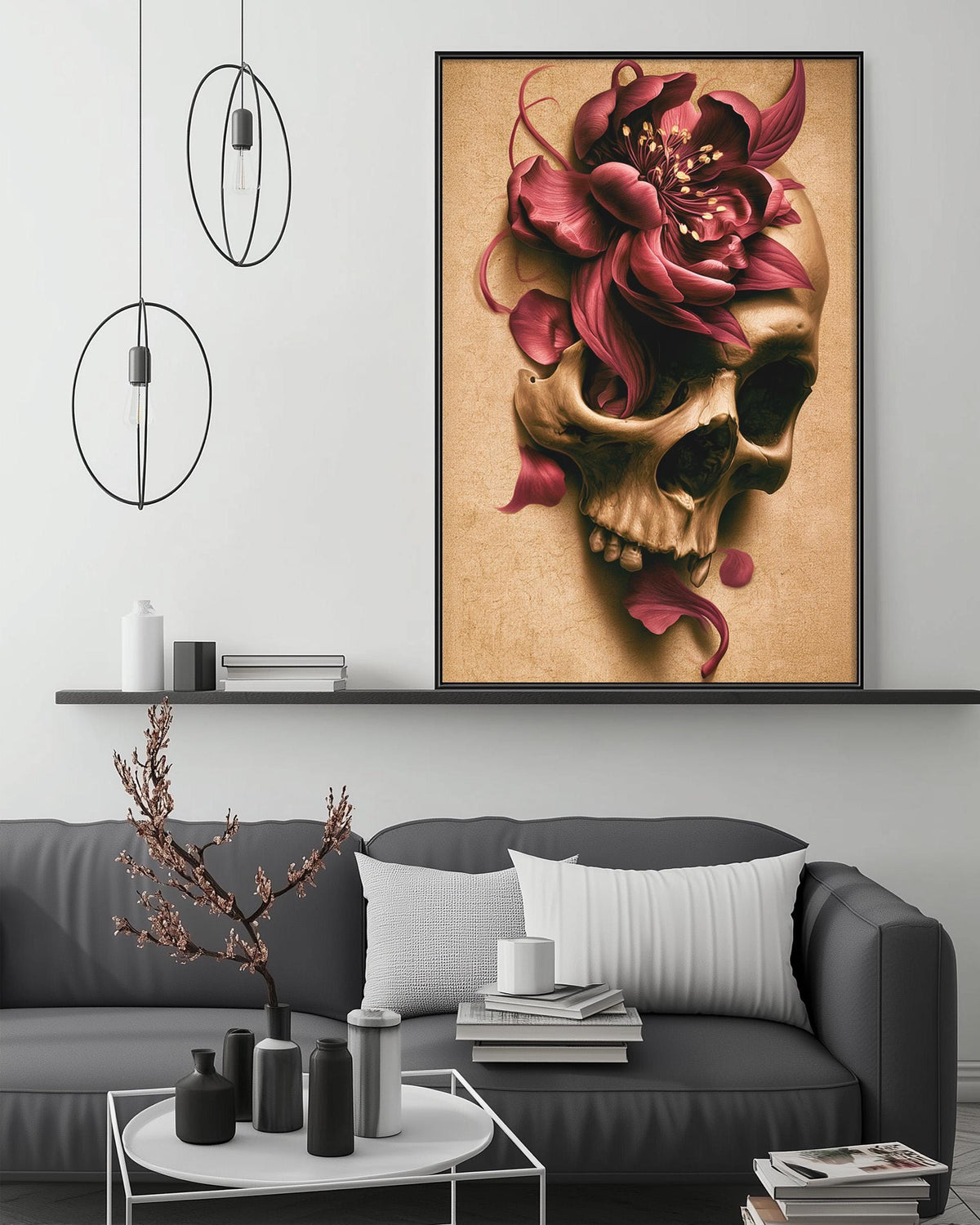 a large framed artwork of a skull with a red flower on its face, hanging on a wall above a gray couch in a living room setting.