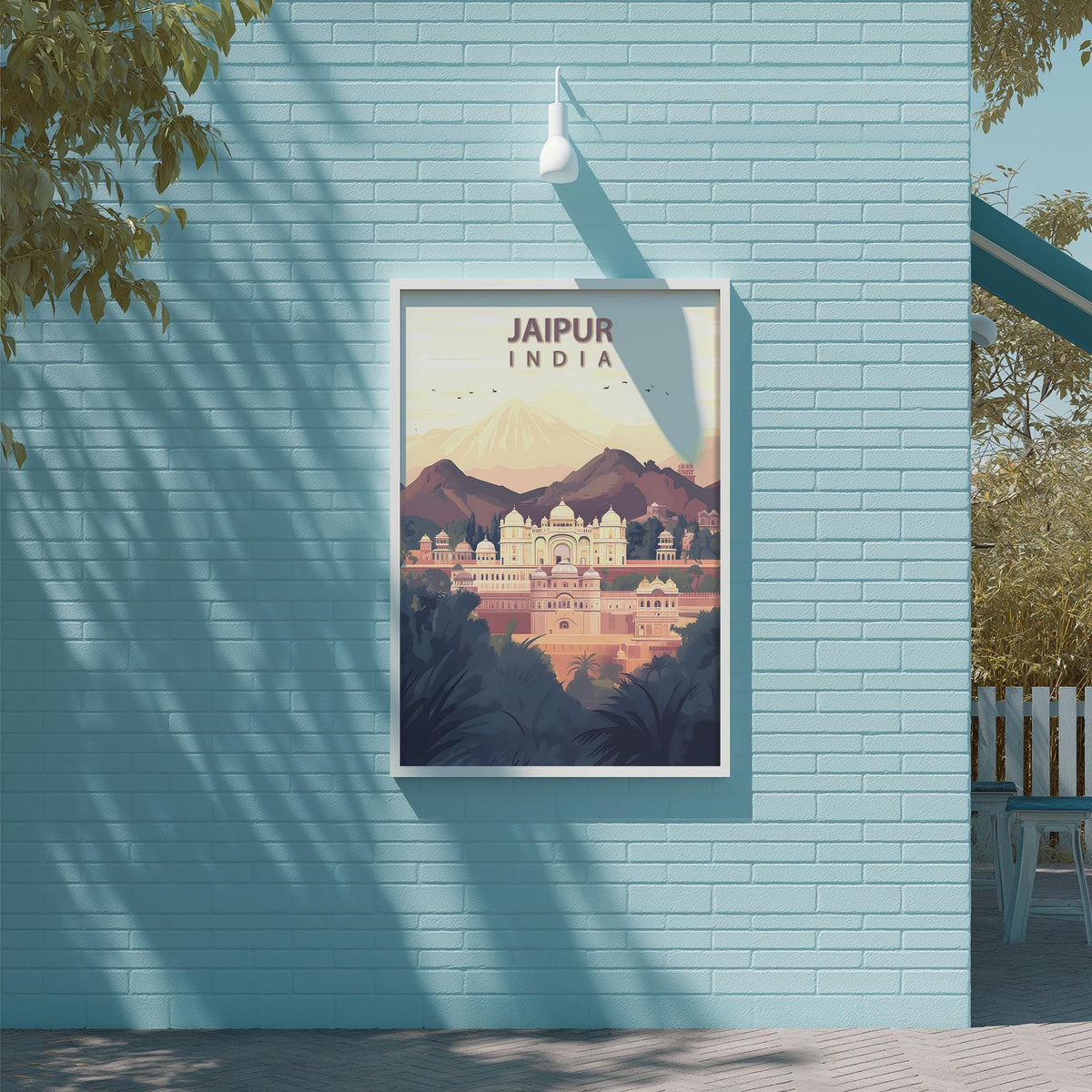 A framed poster of the city of Jaipur, India, displayed on a light blue brick wall.