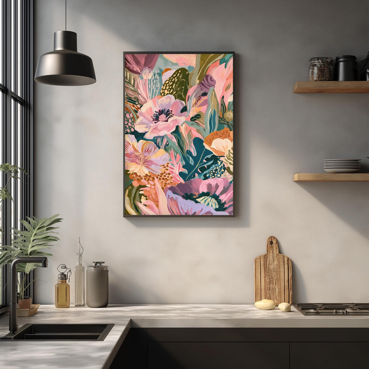 a kitchen counter with a framed colorful painting of flowers hanging above it. The painting has a vibrant mix of pink, green, and orange flowers, creating a lively and cheerful atmosphere. The kitchen counter also has various items such as a cutting board, a bottle, and a bowl, suggesting a functional and organized space.