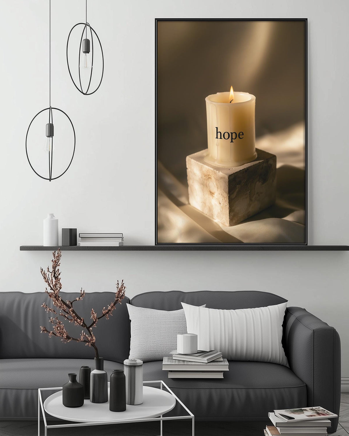 a cozy living room with a gray sofa, a coffee table, and a large framed picture of a lit candle on a stone pedestal. The room has a minimalist and modern design, with a black and white color scheme and a few decorative elements such as a potted plant and a stack of books.
