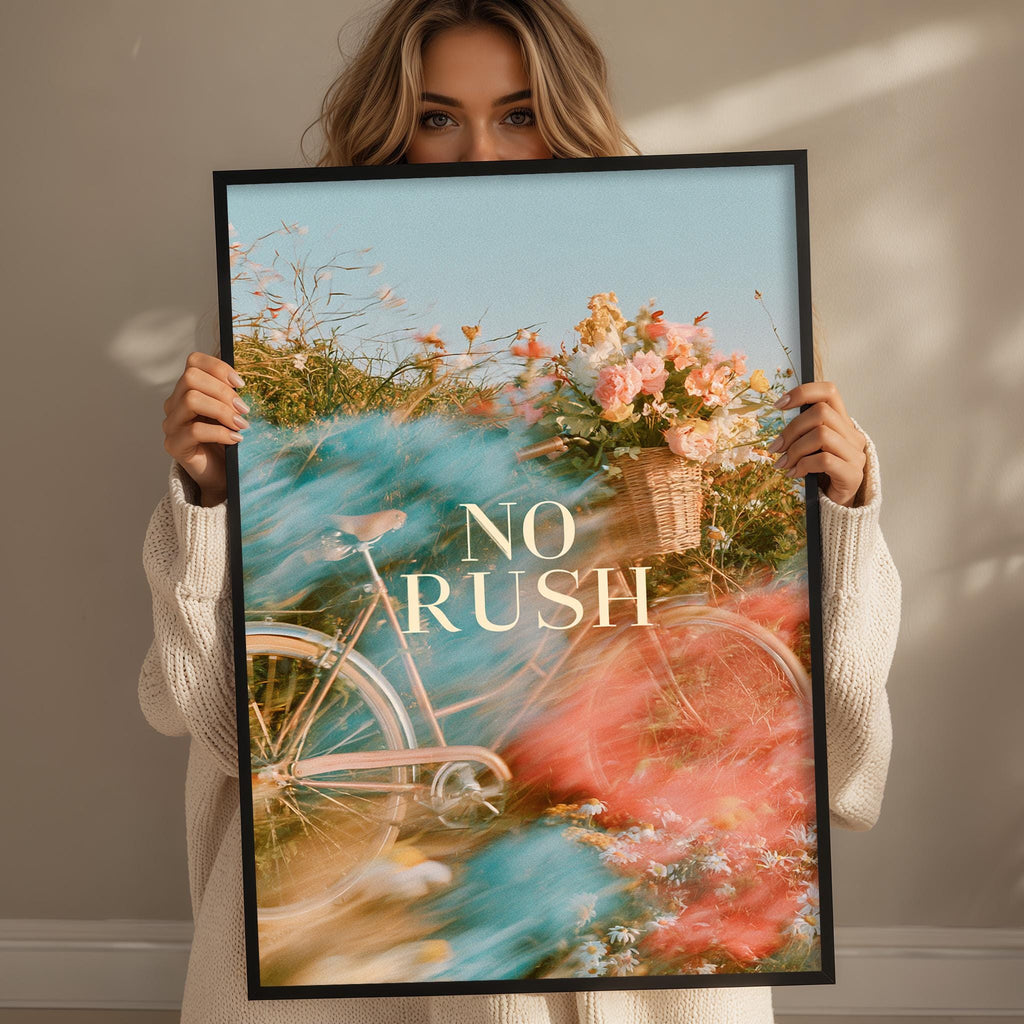 A woman holding a framed poster with a bicycle and flowers in the background.