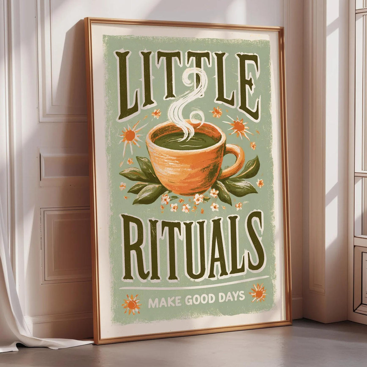 A framed poster with the text "LITTLE RITUALS MAKE GOOD DAYS" and an illustration of a cup of tea with steam rising from it.