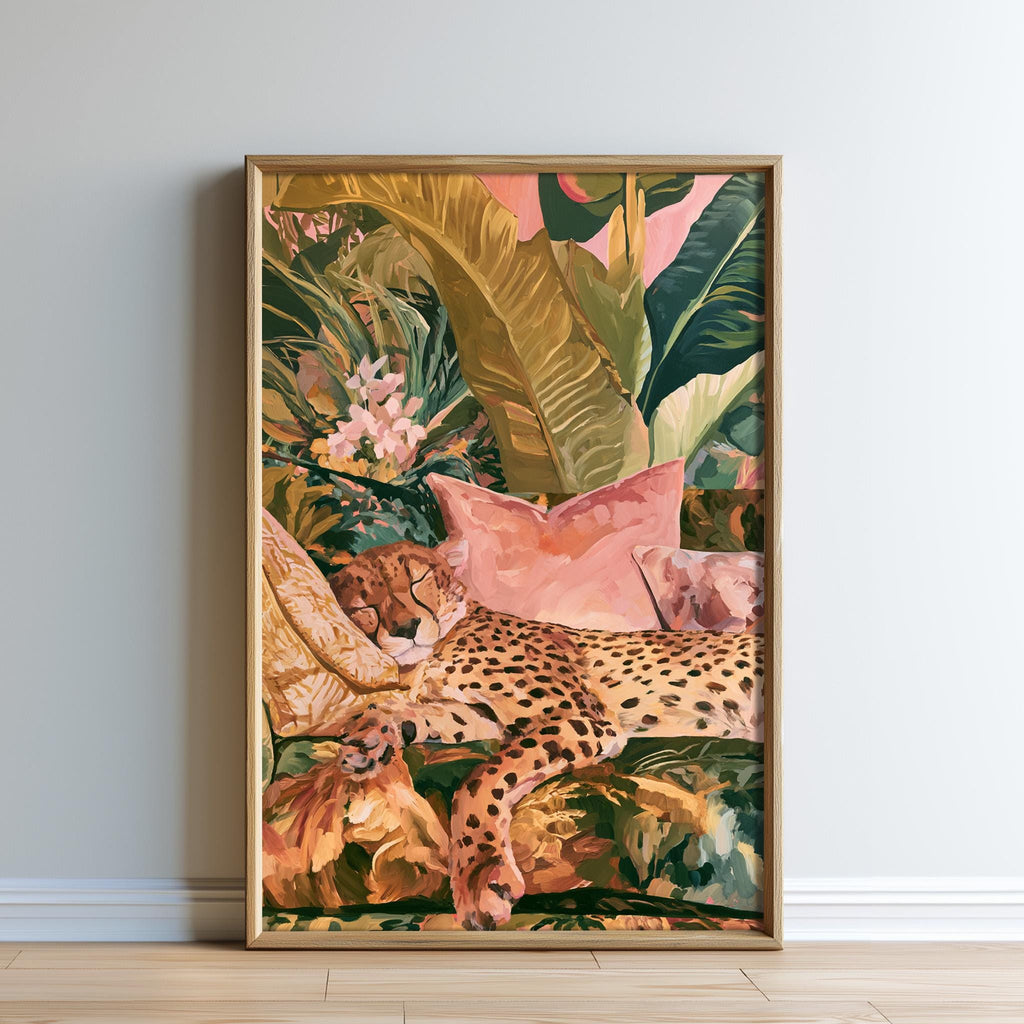 A framed print depicting a leopard resting on a bed of tropical foliage, with a pink pillow and a green plant in the background.