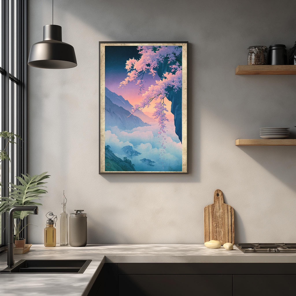 a kitchen counter with a framed painting of a mountain landscape hanging above it. The painting has a vibrant color palette, with shades of blue, pink, and green. The kitchen counter also has various items on it, including a cutting board, a bottle, and a vase.