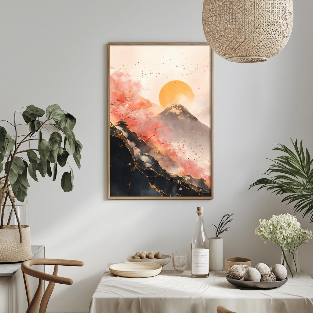 a dining table with a white tablecloth, a bowl of fruit, a bottle, and a vase with flowers. Above the table, there is a framed painting depicting a mountain landscape with a sunset.