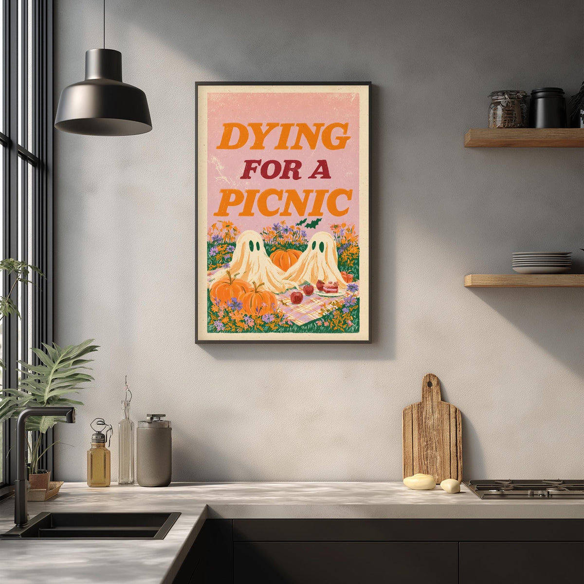 a kitchen counter with various kitchen items, such as a cutting board, a bottle, and a bowl. Above the counter, there is a framed poster with the text " Dying for a Picnic" and an illustration of two ghostly figures.
