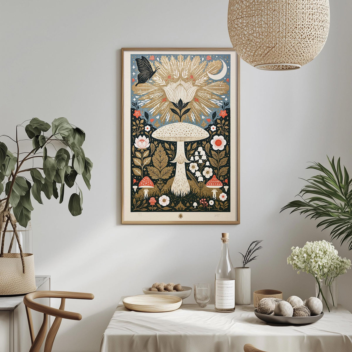 a dining table with a white tablecloth, a bowl of fruit, a bottle, and a vase with flowers. Above the table, there is a framed picture hanging on the wall, depicting a mushroom surrounded by various flowers and plants.