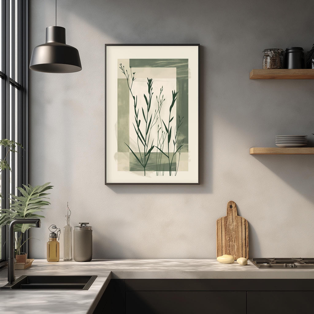 a kitchen counter with a framed print of green plants hanging above it, a wooden cutting board, and various kitchen items such as a bottle, a vase, and a bowl.