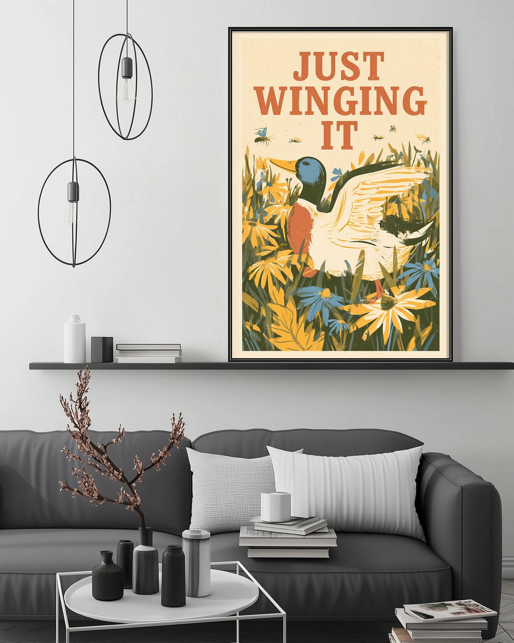 a framed poster with a duck and flowers hanging on a wall above a gray couch with a coffee table in front of it.