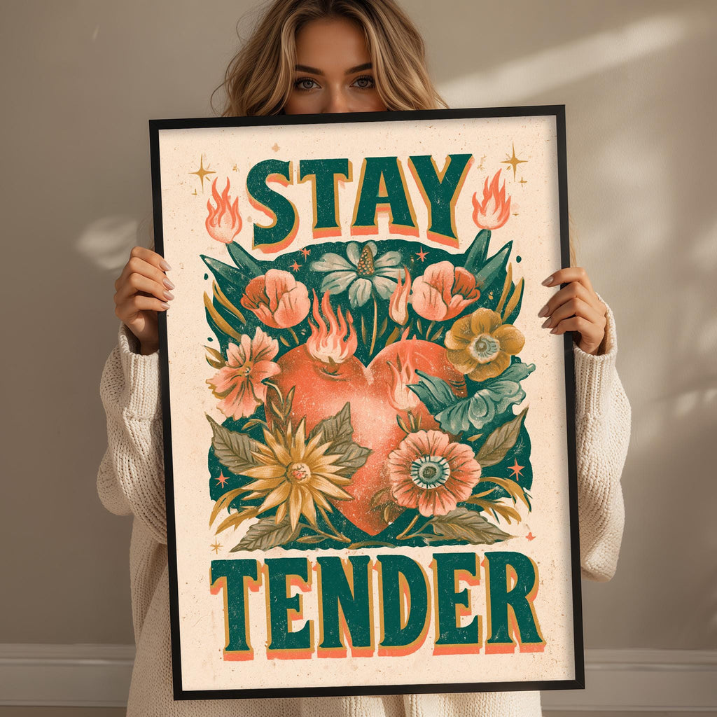 A woman holding a framed poster with a floral design and the text "STAY TENDER" on it.