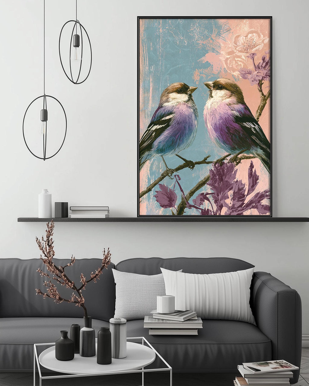 a cozy living room with a gray sofa, a coffee table, and a large framed painting of two birds perched on a branch with flowers. The painting is hanging above the sofa, creating a focal point in the room.